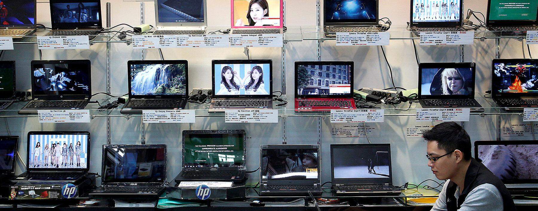 A shop attendant sits in front of a wall of laptops at a computer mall in Taipei