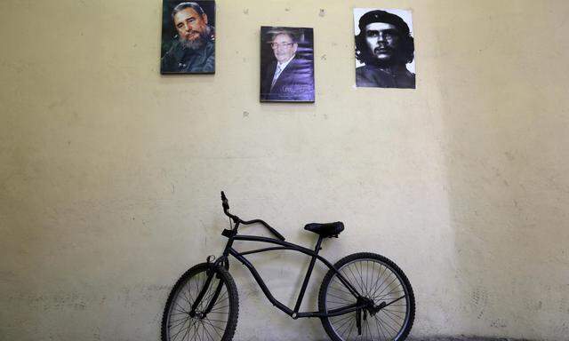 A bicycle is parked under pictures of Cuba´s former president Fidel Castro, Raul Castro, brother of Fidel and Cuba´s president, and revolutionary hero Ernesto ´Che´ Guevara in an office in Havana