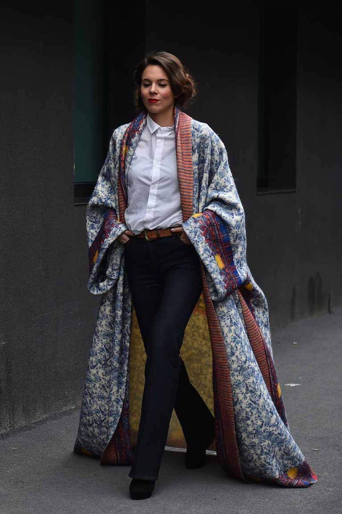 Abseits der Laufstege wollen die Besucher der Modewoche und selbsternannte Fashionistas vor allem eines: auffallen um jeden Preis. Eine Art überlanger Kimono macht auch einfache Outfits interessant.