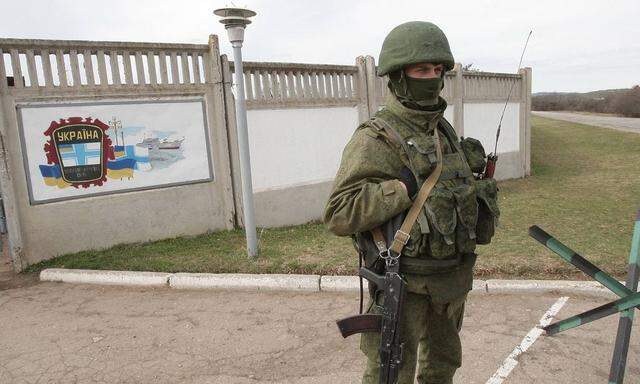 An armed man who is believed to be a Russian soldier stays outside the besieged base of the 36th Sep