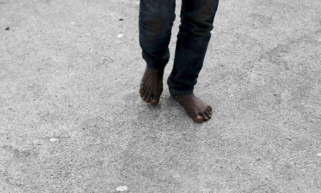 A migrant walks barefoot after arriving by boat at the Sicilian harbour of Pozzallo