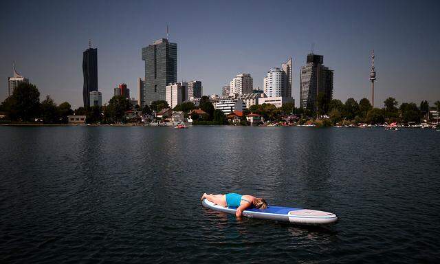 A woman rests on a surfboard at Alte Donau, an abandoned meander of river Danube during a heat wave in Vienna