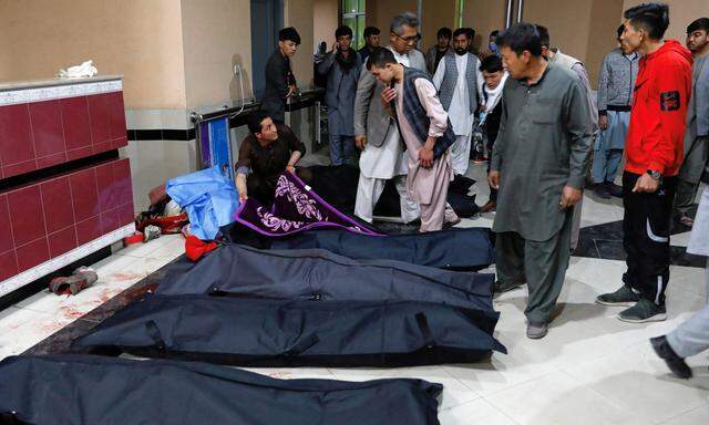 Afghan men look for their relatives at a hospital after a suicide bombing in Kabul