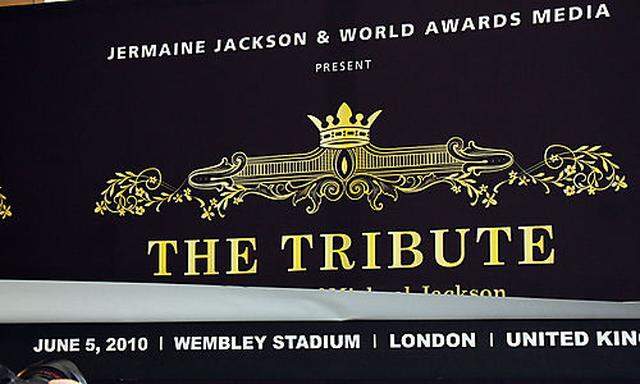 The new date for The Tribute concert is seen beyond the background poster of a press conference in 