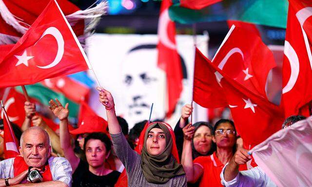 Supporters of Turkish President Erdogan wave national flags as they listen to him through a giant screen in Istanbul´s Taksim Square