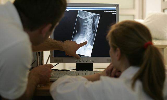 Doctors discuss medical treatment as they look at an X-Ray image on a monitor outside the emergency room of the Unfallkrankenhaus Berlin hospital