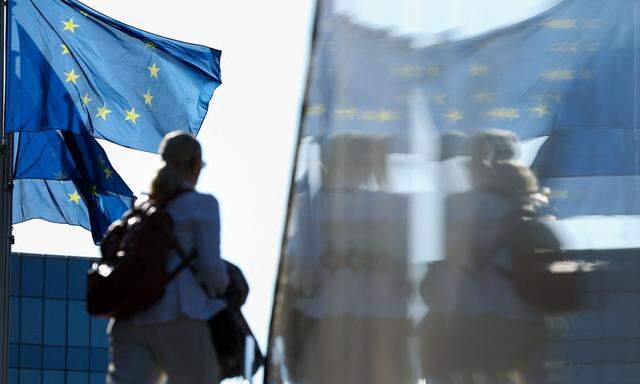 A woman passes by flags of the European Union outside the European commission headquarters in Brussels on May 11, 2022. (Photo by Kenzo TRIBOUILLARD / AFP)