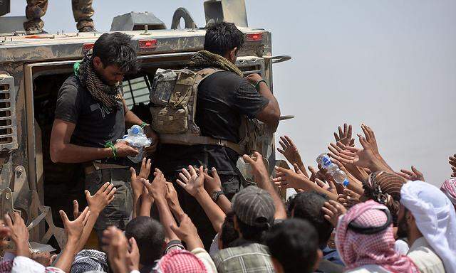 Irakische Sicherheitskräfte verteilen Wasser an Flüchtlinge.
