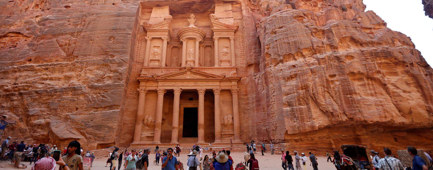 Tourists take pictures in front of the treasury site in the ancient city of Petra, south of Amman