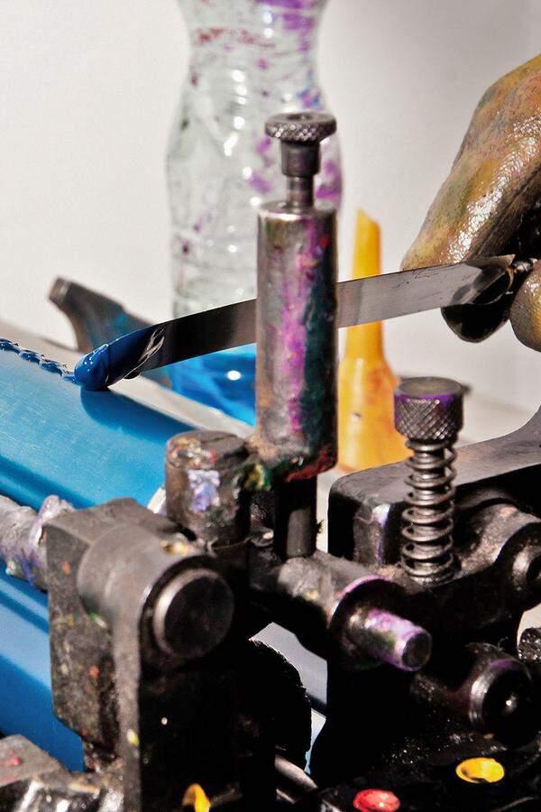 Die Farben werden händisch mit einer Spachtel auf die Walzen der Maschine aufgetragen.