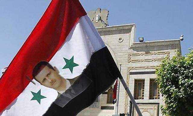 Ein Porträt des syrischen Präsidenten Assad auf einer Fahne vor dem Parlament in Damaskus