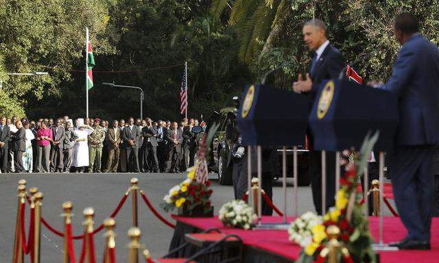 Kenyan staff members look on as Obama and Kenyatta hold a joint news conference after their meeting at the State House in Nairobi