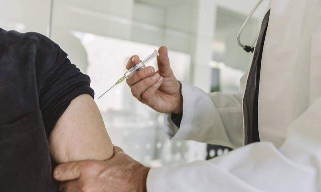 Doctor injecting vaccine into senior patient´!s arm model released Symbolfoto property released MFF05451