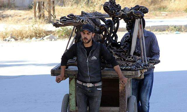 Vendors push their cart along a passageway separating Aleppo's Bustan al-Qasr and Al-Masharqa neighborhood