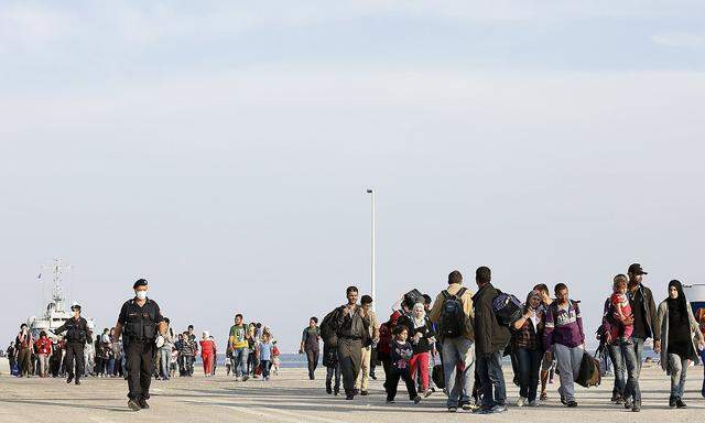 Syrian refugees are escorted by Carabinieri after disembarking from Belgian Navy vessel Godetia at the Augusta port, Italy