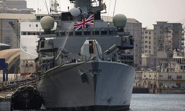 Members of the British Royal Navy frigate HMS Westminster spray water with a hose to clean the ship after arriving at a port in Gibraltar