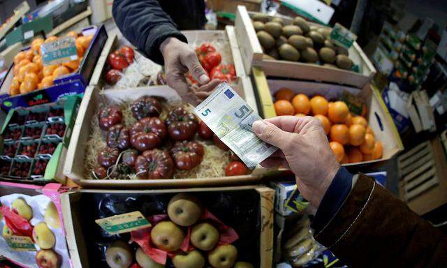 FILE PHOTO: A shopper pays with a Euro bank note in a market in Nice