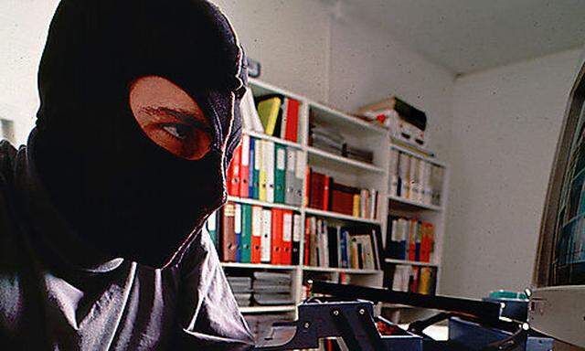 Mann mit Maske sitzt vor einem Computer-Computerkrimineller 