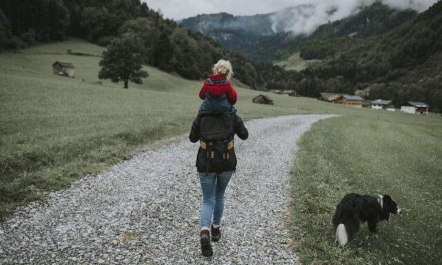 Austria, Vorarlberg, Mellau, mother carrying toddler on shoulders on a trip in the mountains