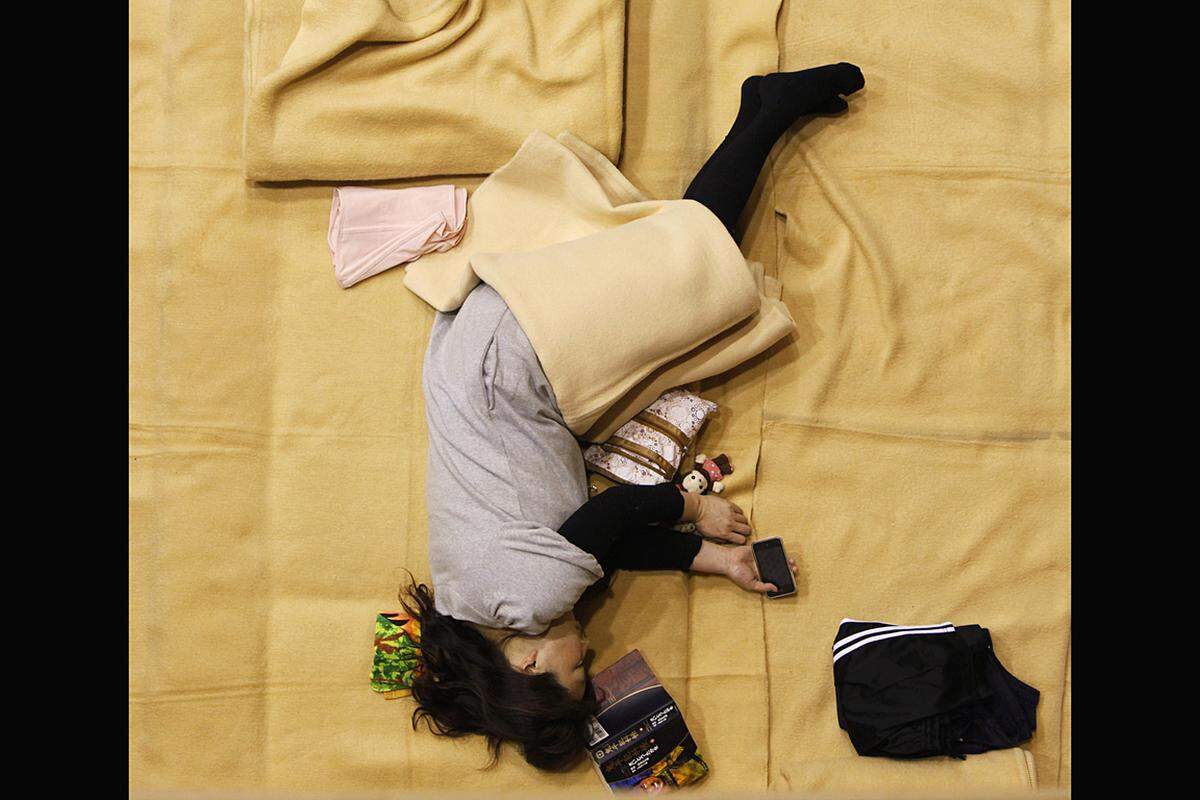 Im einem Turnsaal des Ajinomoto-Stadions in Chofu schläft eine Frau, kurz bevor Kronprinz Naruhito und Kronprinzessin Masako die Notunterkunft besuchen. (6. April)