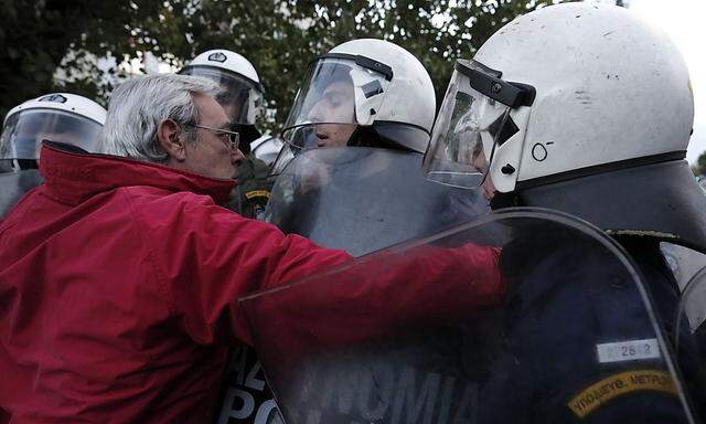 A protester scuffles with policemen as he tries to approach the headquarters of state television ERT at Agia Paraskevi suburb north of Athens