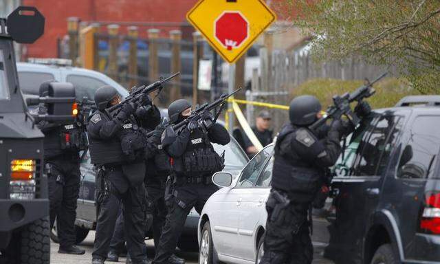 Police officers take position during a search for the Boston Marathon bombing suspects in Watertown