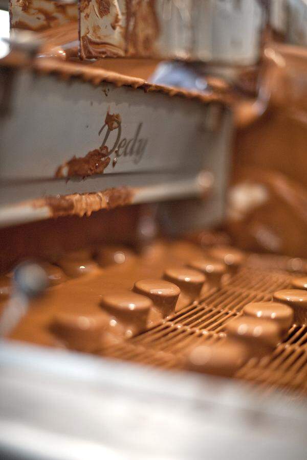 In der Tunkmaschine wird das gefüllte Konfekt mit Schokolade überzogen.