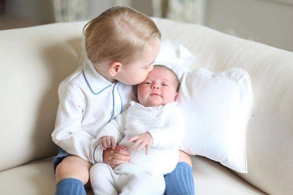 Das britische Königshaus hatte schon am 6. Juni die ersten Fotos von Prinzessin Charlotte gemeinsam mit ihrem großen Bruder Prinz George veröffentlicht. Eines zeigt, wie George Charlotte auf dem Schoß hat und ihr ein Küsschen auf die Stirn drückt.