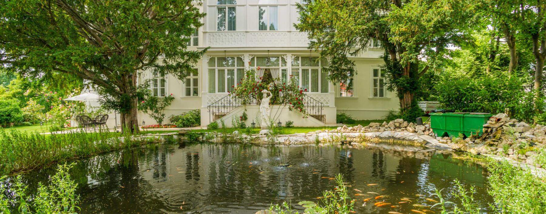 Villa in Baden samt Rosenbogen und Koi-Teich im Garten.