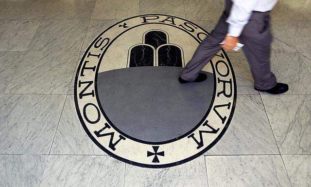 A man walks on a logo of the Monte Dei Paschi Di Siena bank in Rome