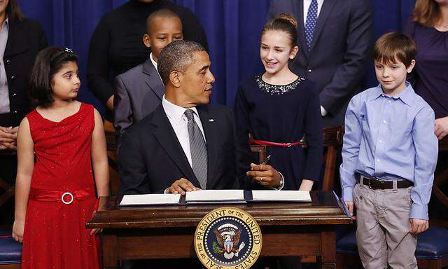 President Barack Obama talks with Julia Stokes as he signs executive orders on gun violence flanked by Hinna Zeejah, Taejah Goode and Grant Fritz during an event at the White House in Washington