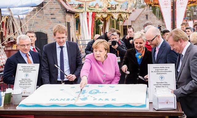 at Die CDU greift zum Messer: Angela Merkel schneidet die Torte im Hansa-Park an, der Mann links neben ihr ist Daniel Günther, CDU-Spitzenkandidat in Schleswig-Holstein.