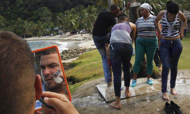 A Cuban migrant shaves his beard as others freshen up after they crossed the border from Colombia through the jungle into La Miel, in the province of Guna Yala, Panama