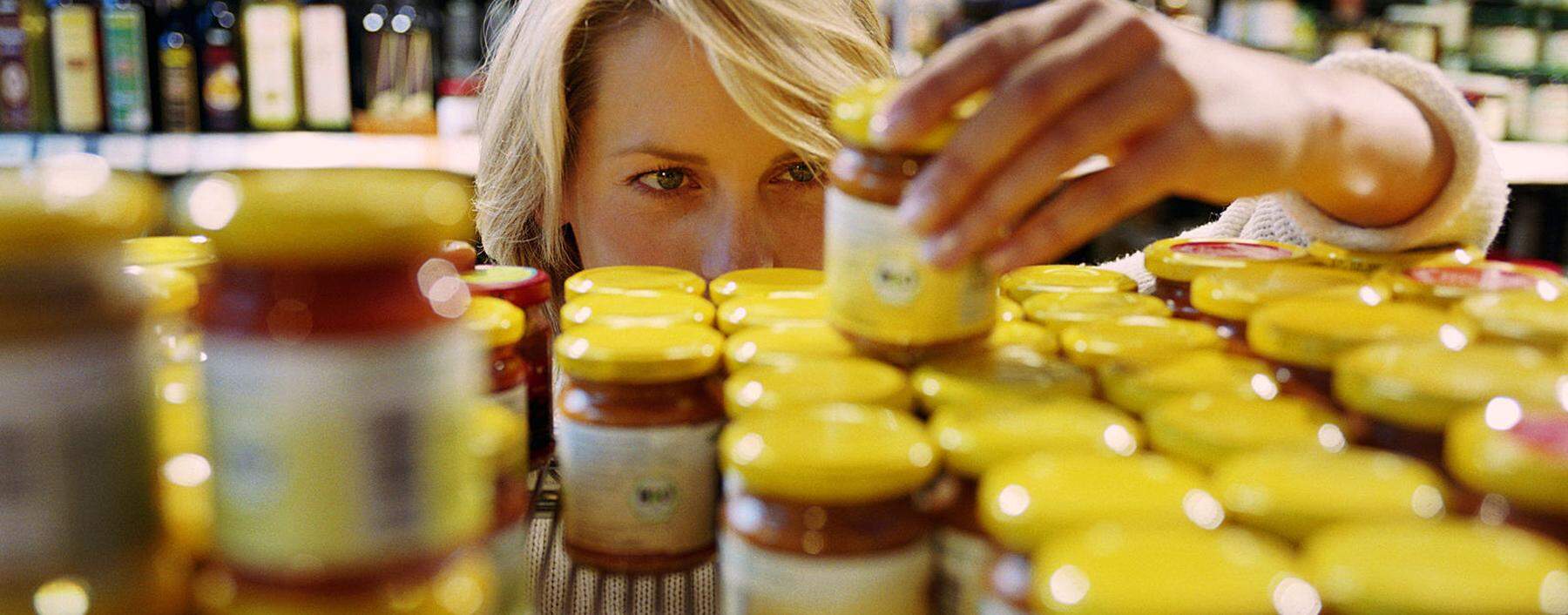 Young woman selecting jar from shelf in shop (focus on woman´s face)