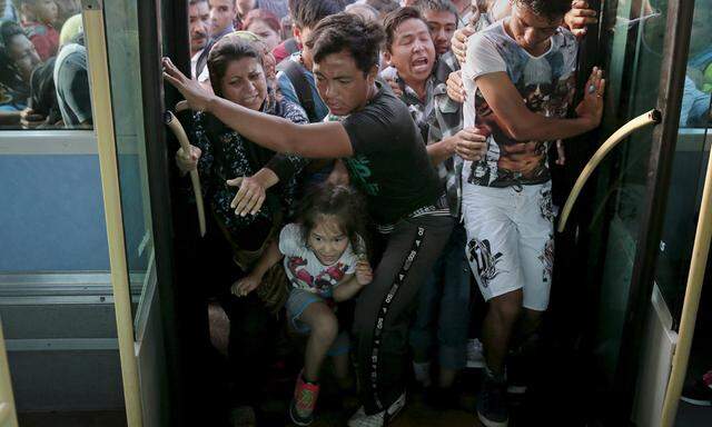 Refugees and migrants push each other as they try to board a bus following their arrival onboard the Eleftherios Venizelos passenger ship at the port of Piraeus