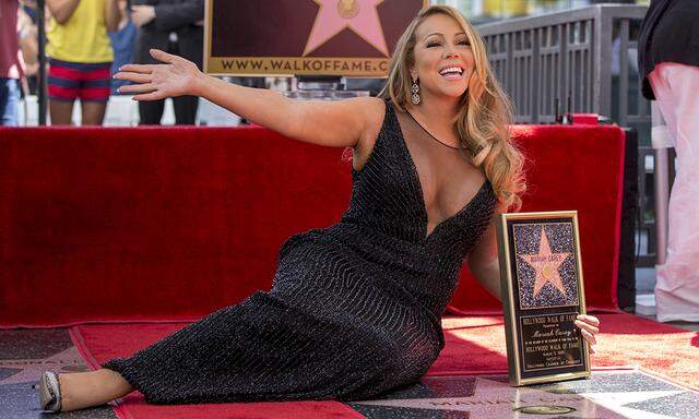 Recording artist Carey poses on her star after it was unveiled on the Hollywood Walk of Fame in Los Angeles