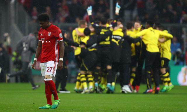 Bayern Munich´s David Alaba looks dejected as Borussia Dortmund players celebrate after the match