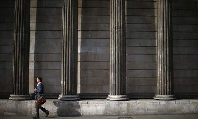A man walks past the columns of the Bank of England in the city of London