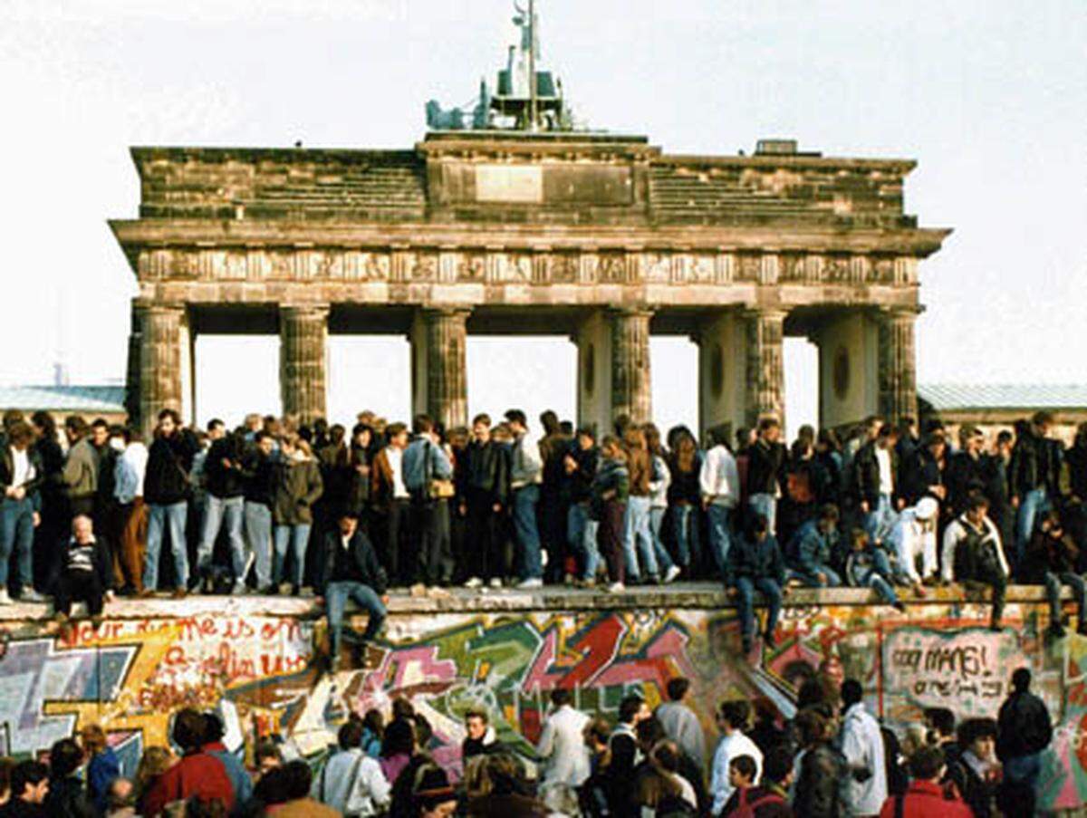 Am Brandenburger Tor halten Tausende Menschen die Panzermauer besetzt.