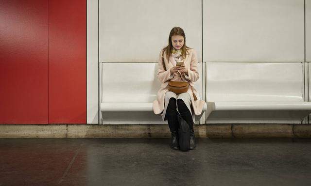 Austria Vienna young woman waiting at underground station using smartphone model released Symbolfo