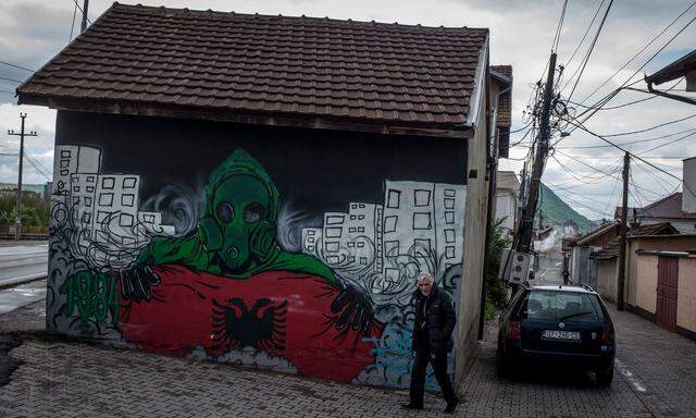 Ein Mann in Mitrovica, Kosovo, spaziert an einem Graffito im albanischen Süden der Stadt vorbei. 