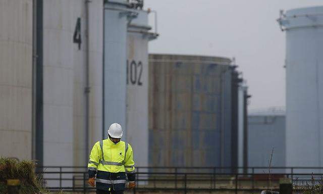 A worker walks past oil tanks at the Total refinery in Grandpuits
