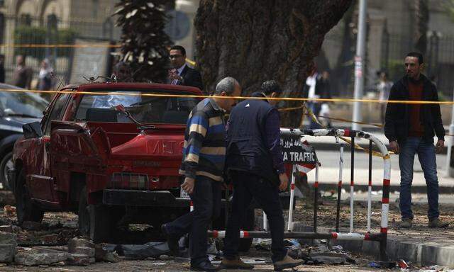 Police officers inspect near the site of a series of explosions in front of Cairo University