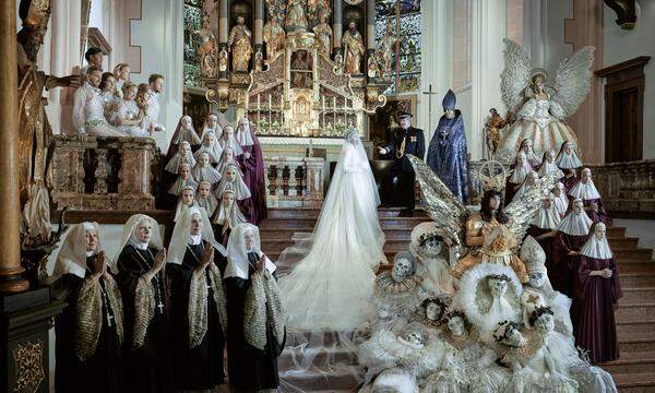 "Die prunk- wie auch liebevolle Hochzeitsszene wird von einer besonderen Lichtgestalt bewacht: Der Erzengel Michael, dem die Basilika St. Mondsee tatsächlich geweiht ist, gilt als der Mächtigste unter den mystischen Wesen, als jener, der dem Schöpfer am nächsten steht. Möge er alle seine Kinder beschützen, egal wen sie lieben. Denn Liebe und wahre Verbundenheit haben in jedem Herzen Raum. Die edelsten aller Gefühle brauchen keinen Segen, sie brauchen keine Erklärung. Aber sie verlangen nach Respekt und einem fruchtbaren Boden, auf dem sie gedeihen können." Models: Rose Alaba, Verena Altenberger, Conchita, Vera Doppler, Herbert Föttinger, Markus Freistätter, Elisabeth Gürtler, Chris Lohner, Missy May, Sunnyi Melles, Zoe Straub, Desirée Treichl-Stürgkh, Nathan Trent, Hanni Bernhard, Ada Dibon, Hanna, Gumpinger, Brigitte Polt, Sofie Steininger, Anna Zehetbauer – Body &amp; Soul, Murat Cavdar, Alexandra Bossanyi, Alina Chlebecek, Klaudia Dimitrijevic, Bianca Ginsberg, Marion Mandl, Winny Nt, Pieter Vestjens – Mother Agency, Mia Thomalla, Nina Authried, Sophie Formanek Max Lang, Yannik Pelzl, Flora Kocher, Aminata Ötsch, Laura Gruber, Laura Igali-Igalffy, Isabella Köck, Andrea Pirker – Stella Models, Atlanta Puntigram, Emma Braun, MarleneDostal, Rosanna Hanke – Tempo Models, Daria Gavric, Antonia Hausmair – Wiener Models, Sarah Baumgartner, Thomas Kaufmann, Manuel Neumann, Julia Reiff, Max Wiplinger Hairdressers: Daniela Baumgartner, Michael Leitner – Sturmayr Coiffeure, Edu von Gomes Make up: Andreas Bernhardt – BASICS Berlin, Monika Labaj, Sarah Smrzek – MAC Cosmetics, Susu Babolleh, Kerstin Bruckmayer, Anita Eder, Angela Jusubowa, Evelyn Karbach, Pia Urbanek, Julia Zielinski Bodypainting / Special Effects: Birgit Mörtl Style Providers: JCH Jürgen Christian Hoerl Location: Basilika St. Mondsee (Pfarre Mondsee), Salzburg Photo: Life Ball / Markus Morianz