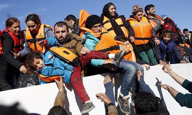 Refugees and migrants try to leave a boat as they arrive on the Greek island of Lesbos
