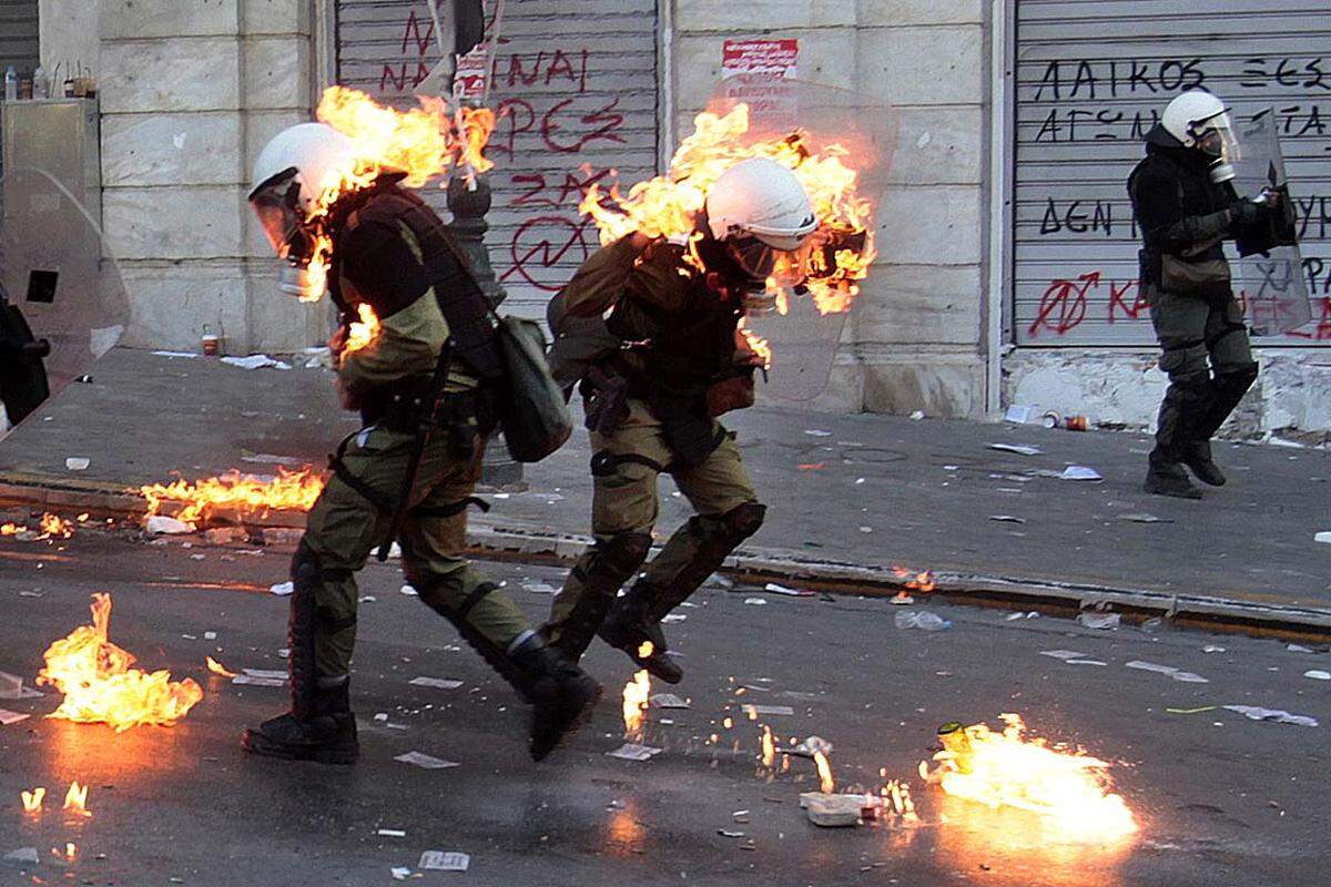 Athen, Griechenland. Zwei Polizisten in Kampfausrüstung stehen in Flammen, nachdem sie in der Nähe des zentralen Syntagma-Platzes von Demonstranten mit Benzinbomben beworfen worden sind.