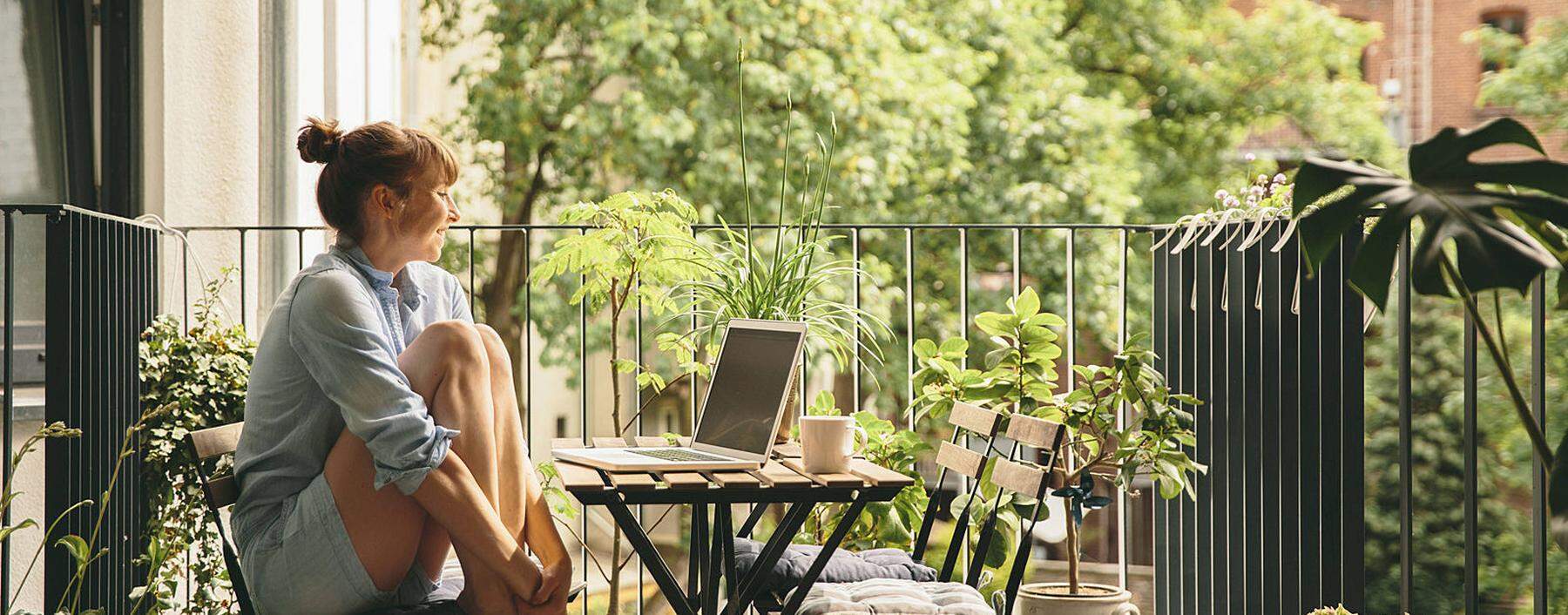 Smiling woman looking at her laptop on balcony model released Symbolfoto property released PUBLICATI