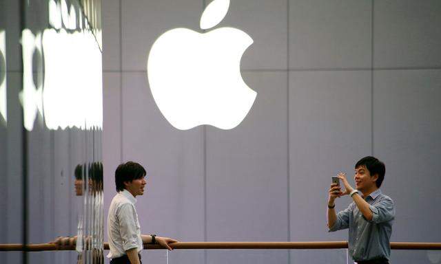 A man uses his phone to take pictures outside an Apple store in Beijing