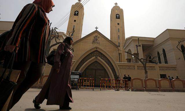 Women pass by the Coptic church that was bombed on Sunday in Tanta