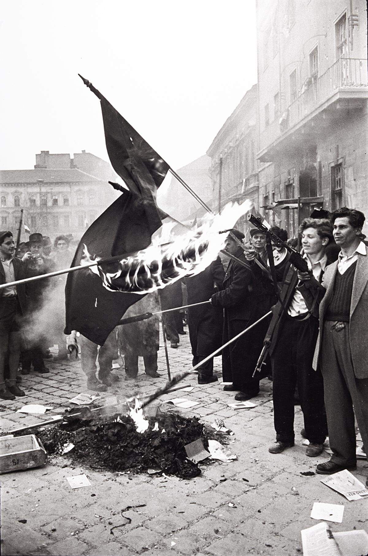 Noch in der Nacht macht die Parteispitze überraschend den 1955 wegen seiner Reformbestrebungen abgesetzten Imre Nagy erneut zum Regierungschef. Erich Lessing: Sowjetische Fahnen werden nach der Besetzung der Zentrale der kommunistischen Partei verbrannt, Kőztársaság-Platz, Budapest 30. Oktober 1956